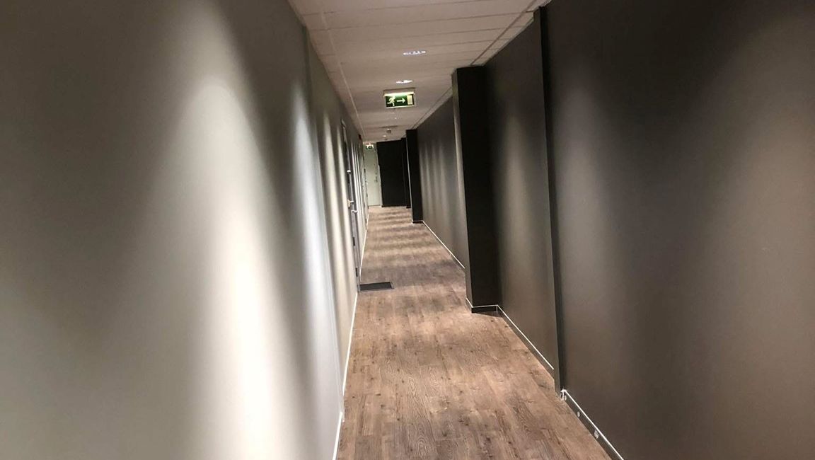 Lang gang med tregulv og mørke vegger.